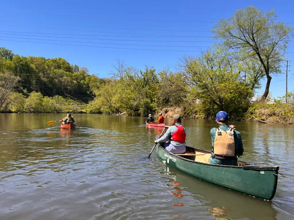 Calm river with kayakers enjoying outdoor adventure in scenic nature.