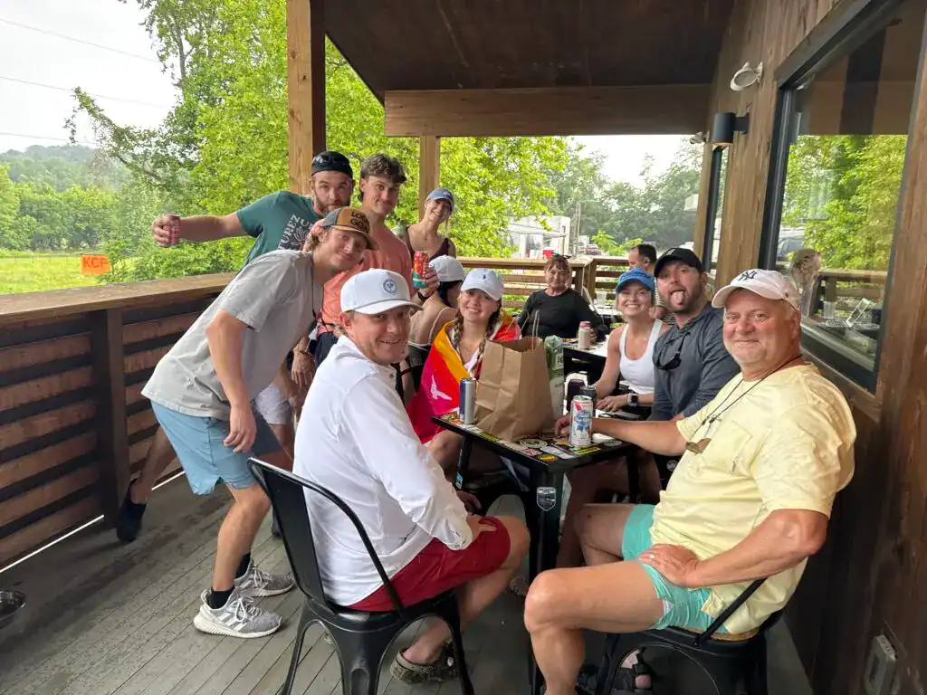 Relaxing group enjoying outdoor dining at Cedar Rock Adventures resort, surrounded by lush greenery and scenic mountain views.